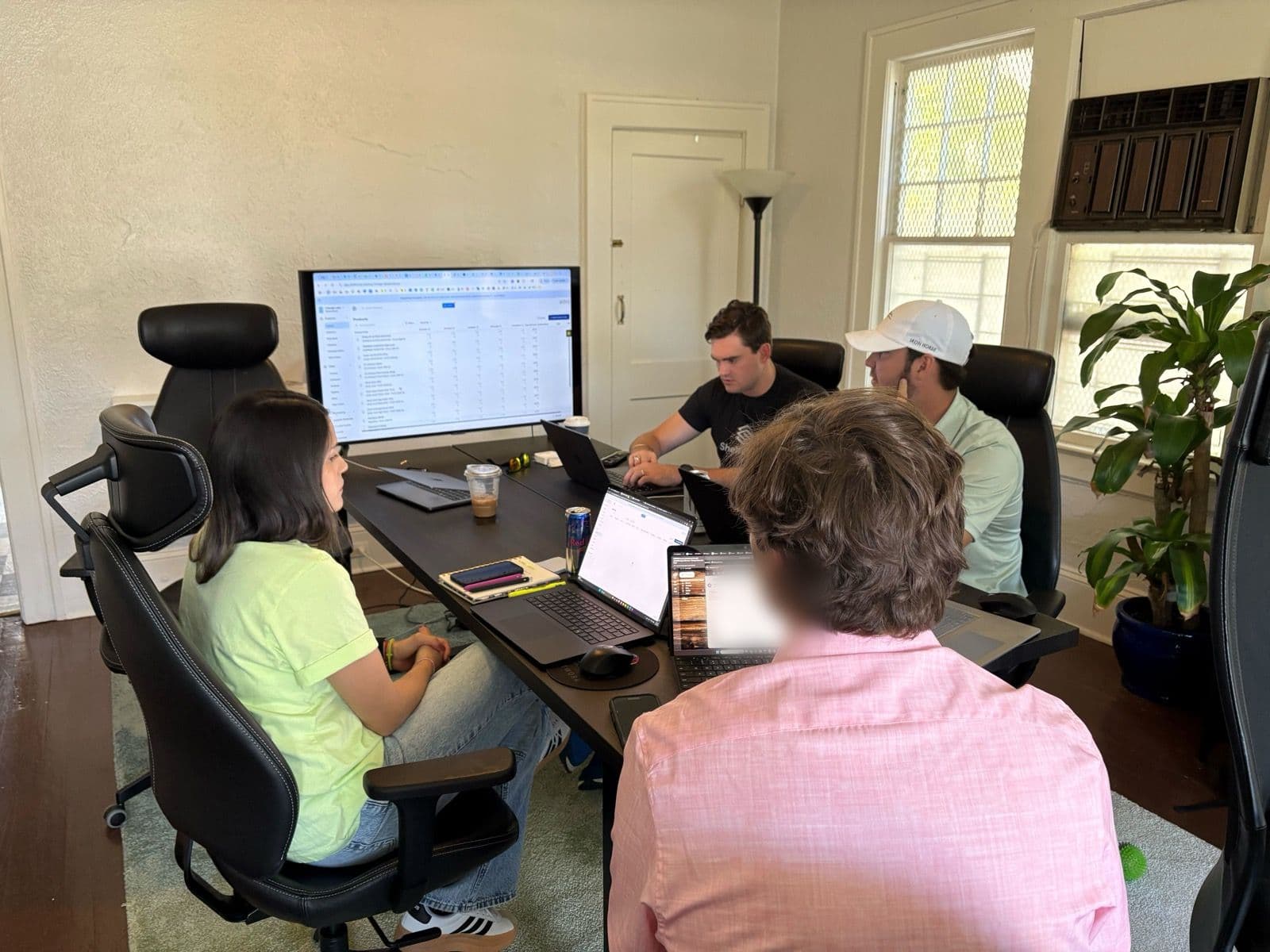 Four ShelfCycle team members around a table, working through a customer's product list on a shared screen